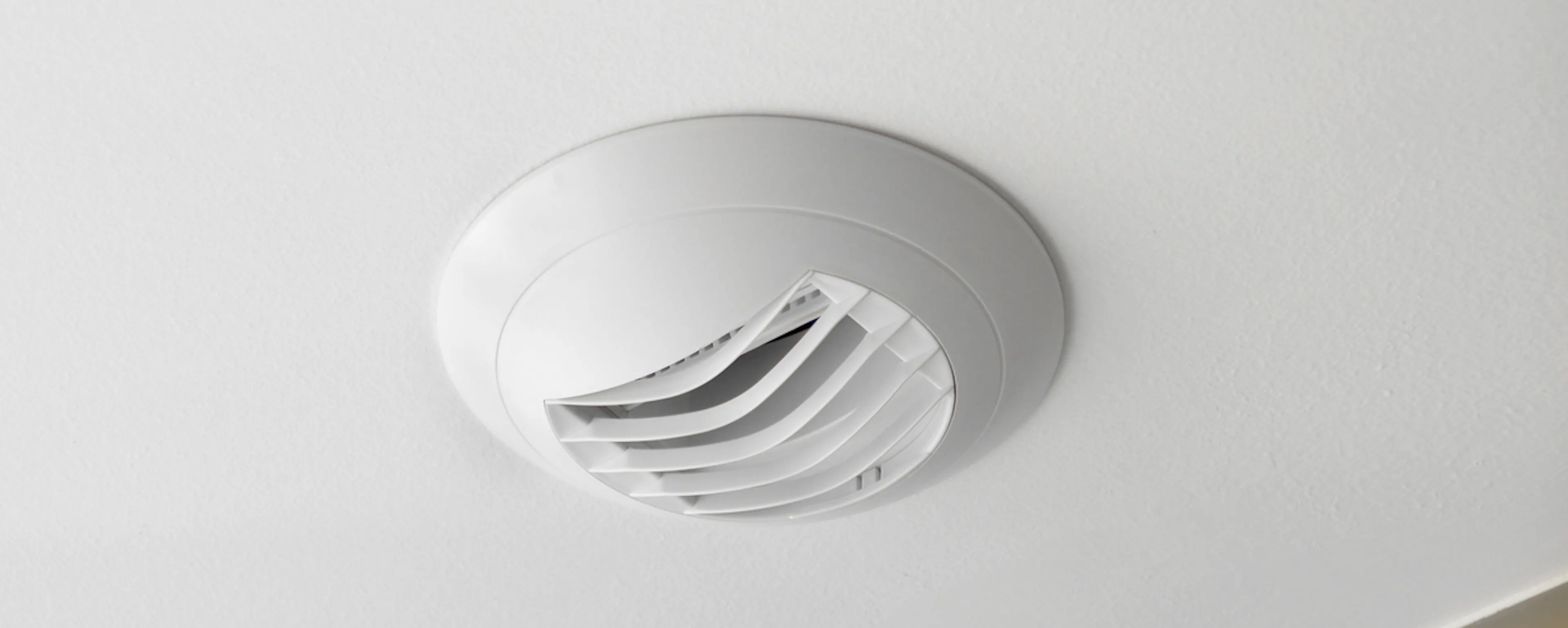 Bouche d'extraction de VMC hygroréglable fixée au plafond d'une salle de bain