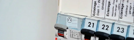 Doigt appuyant sur un disjoncteur dans un tableau électrique