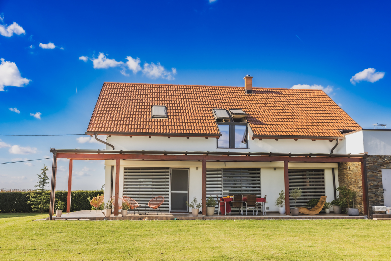 Audit énergétique, différence avec le DPE, à quoi ça sert : photo d'une maison vue depuis son jardin, toit de tuiles, pergola et murs clairs