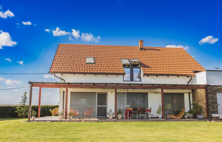 Audit énergétique, différence avec le DPE, à quoi ça sert : photo d'une maison vue depuis son jardin, toit de tuiles, pergola et murs clairs