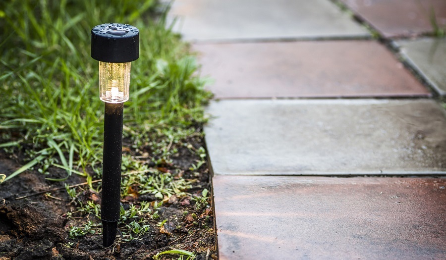 Borne solaire lumineuse plantée dans un jardin le long d'une allée