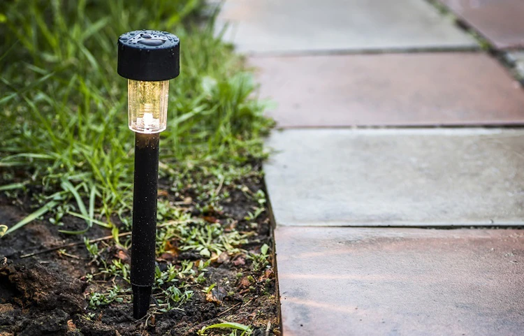 Borne solaire lumineuse plantée dans un jardin le long d'une allée