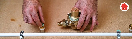 Deux mains installant un réducteur de pression laiton sur une canalisation