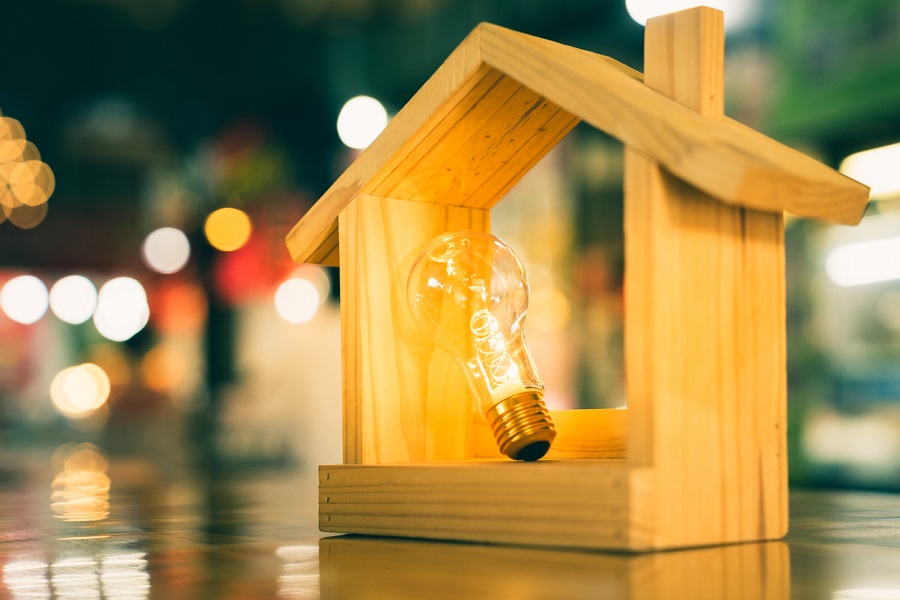 Maquette de maison en bois avec ampoule lumineuse allumée à l'intérieur
