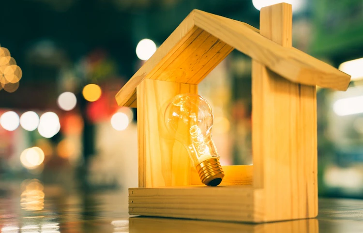 Maquette de maison en bois avec ampoule lumineuse allumée à l'intérieur
