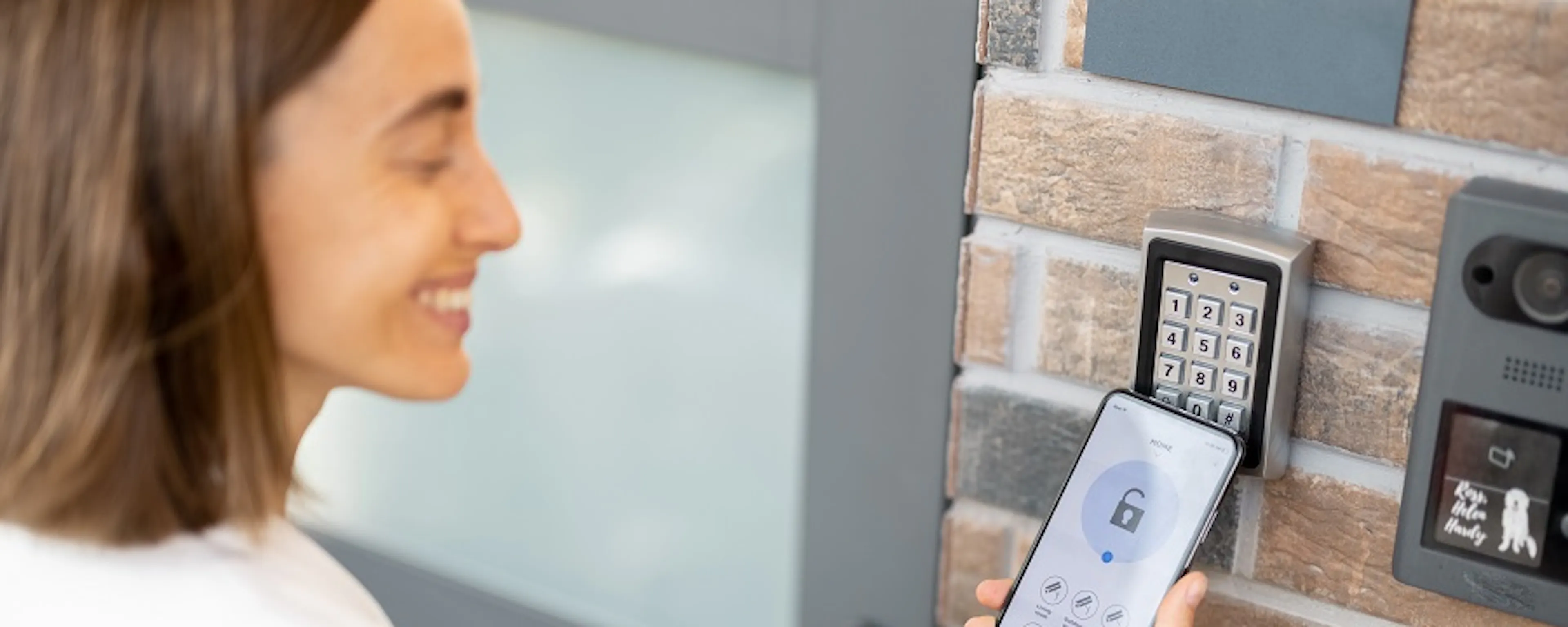 Femme utilisant son smartphone devant un digicode d'entrée sécurisé