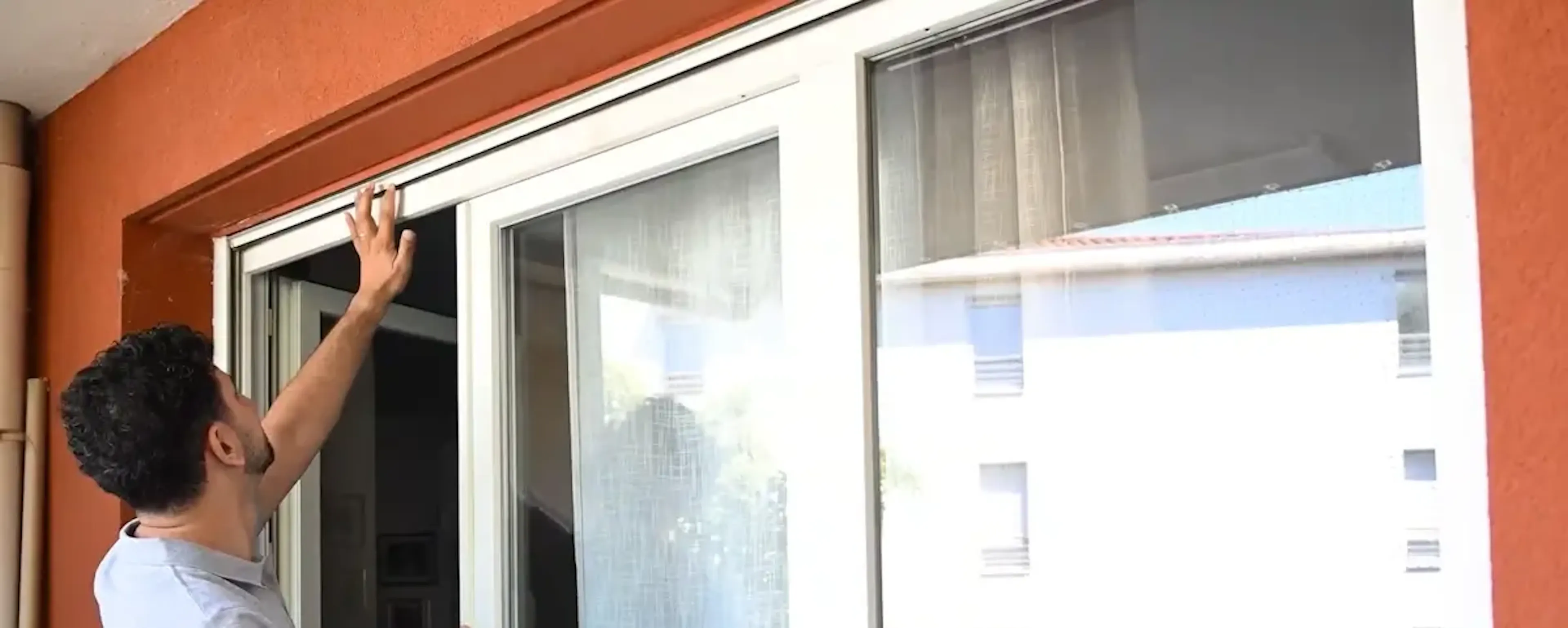 Homme installant une moustiquaire sur une baie vitrée