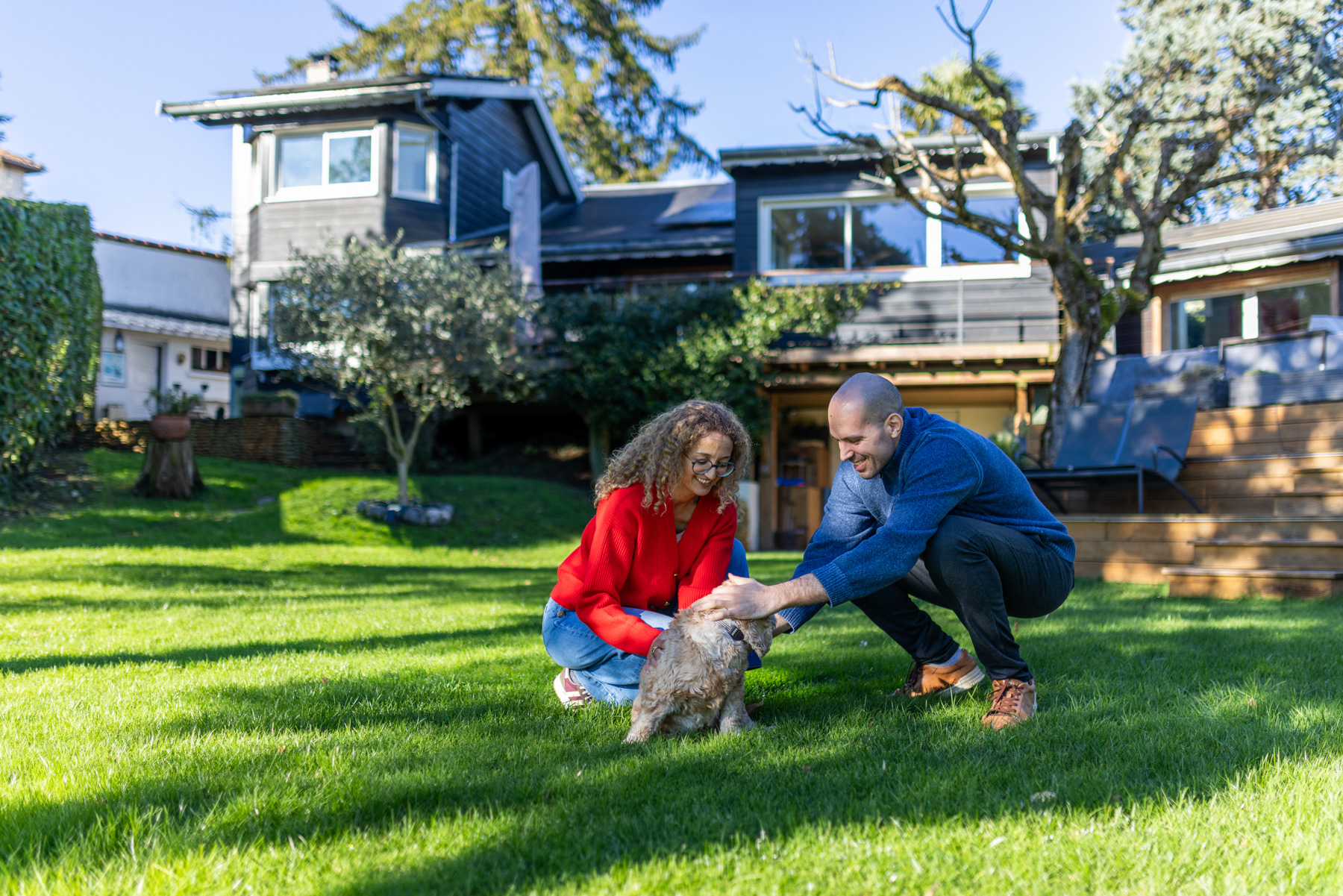 Un couple et leur chien dans leur jardin, devant leur maison rénovée par HomeServe