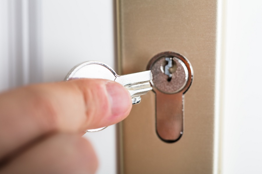 Main insérant une clé dans la serrure d'une porte