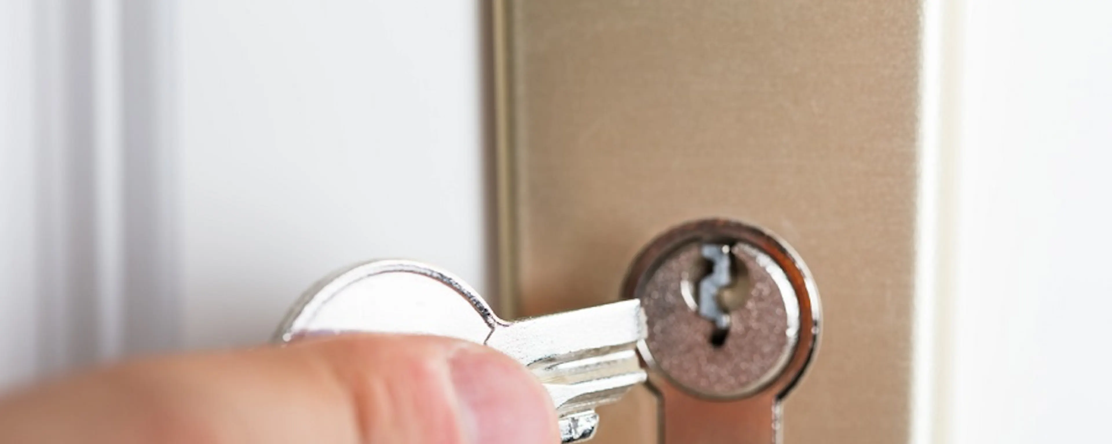 Main insérant une clé dans la serrure d'une porte