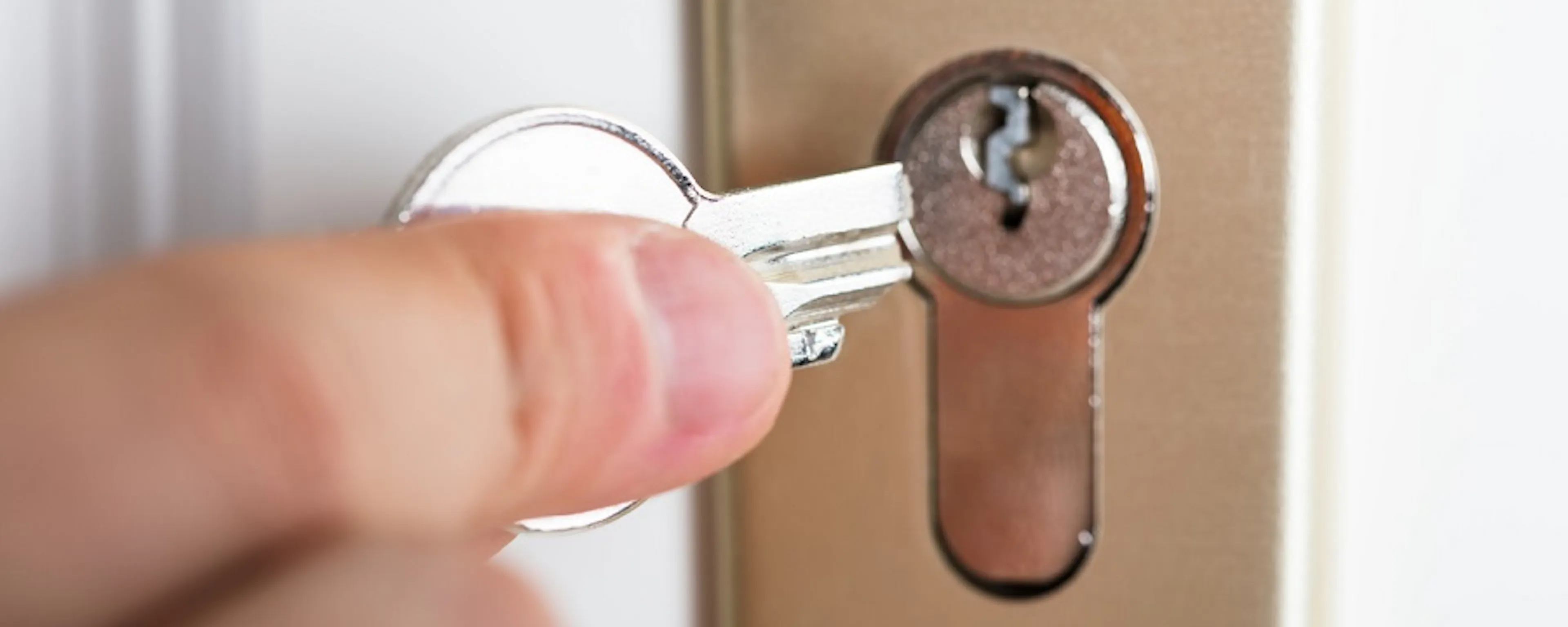 Main insérant une clé dans la serrure d'une porte