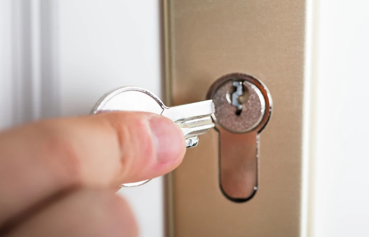 Main insérant une clé dans la serrure d'une porte