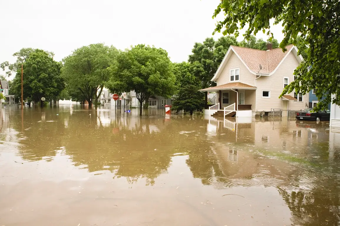 Rue résidentielle inondée avec maisons entourées d'eau boueuse