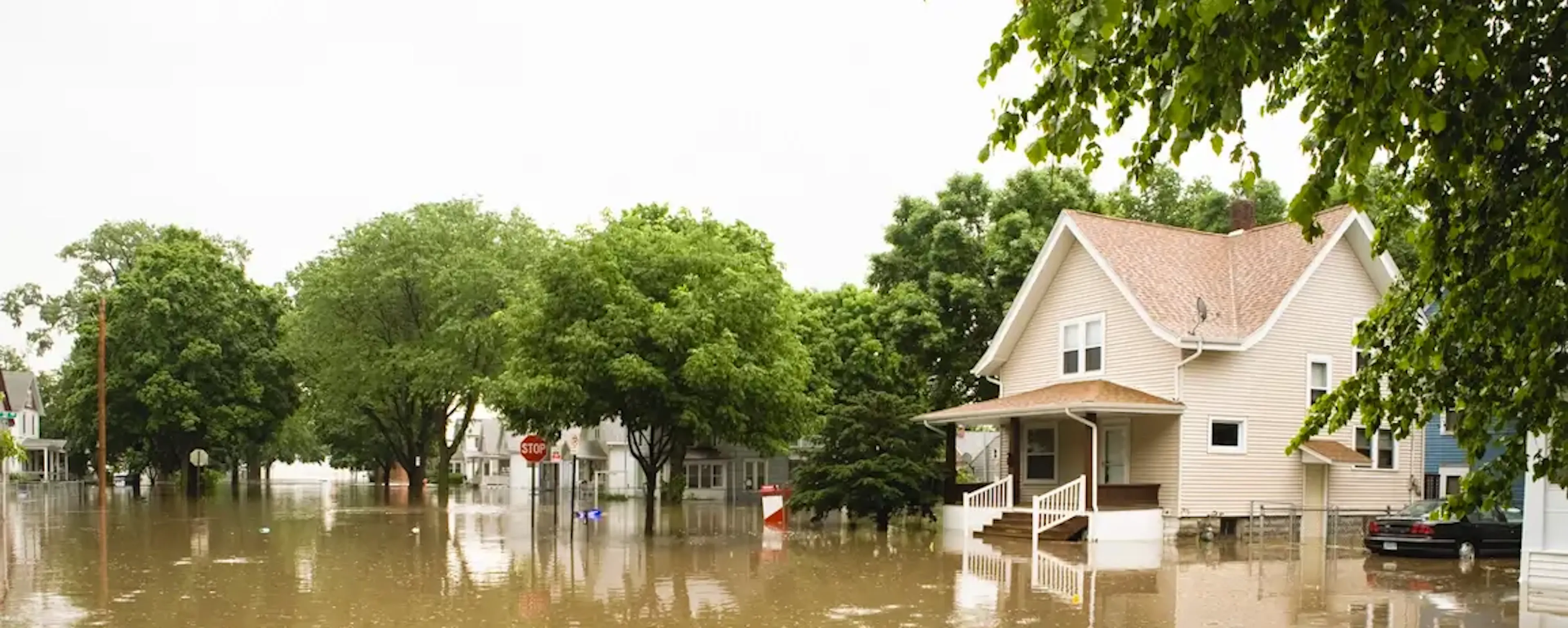 Rue résidentielle inondée avec maisons entourées d'eau boueuse