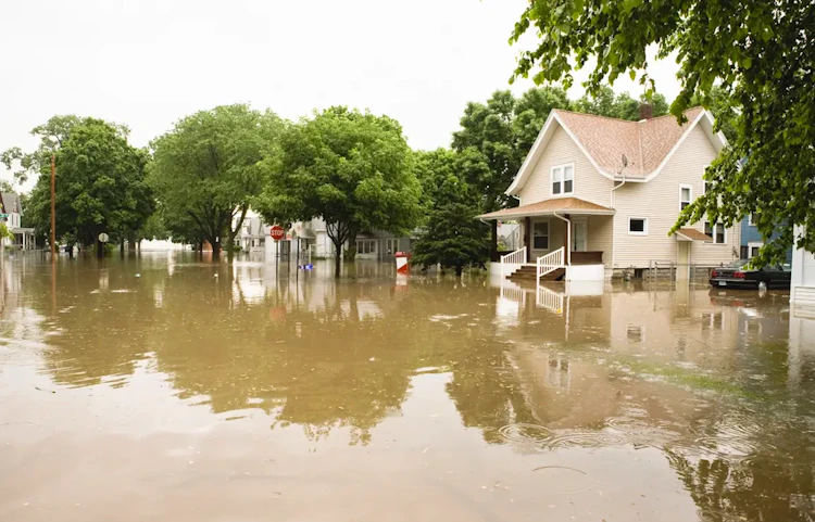 Rue résidentielle inondée avec maisons entourées d'eau boueuse