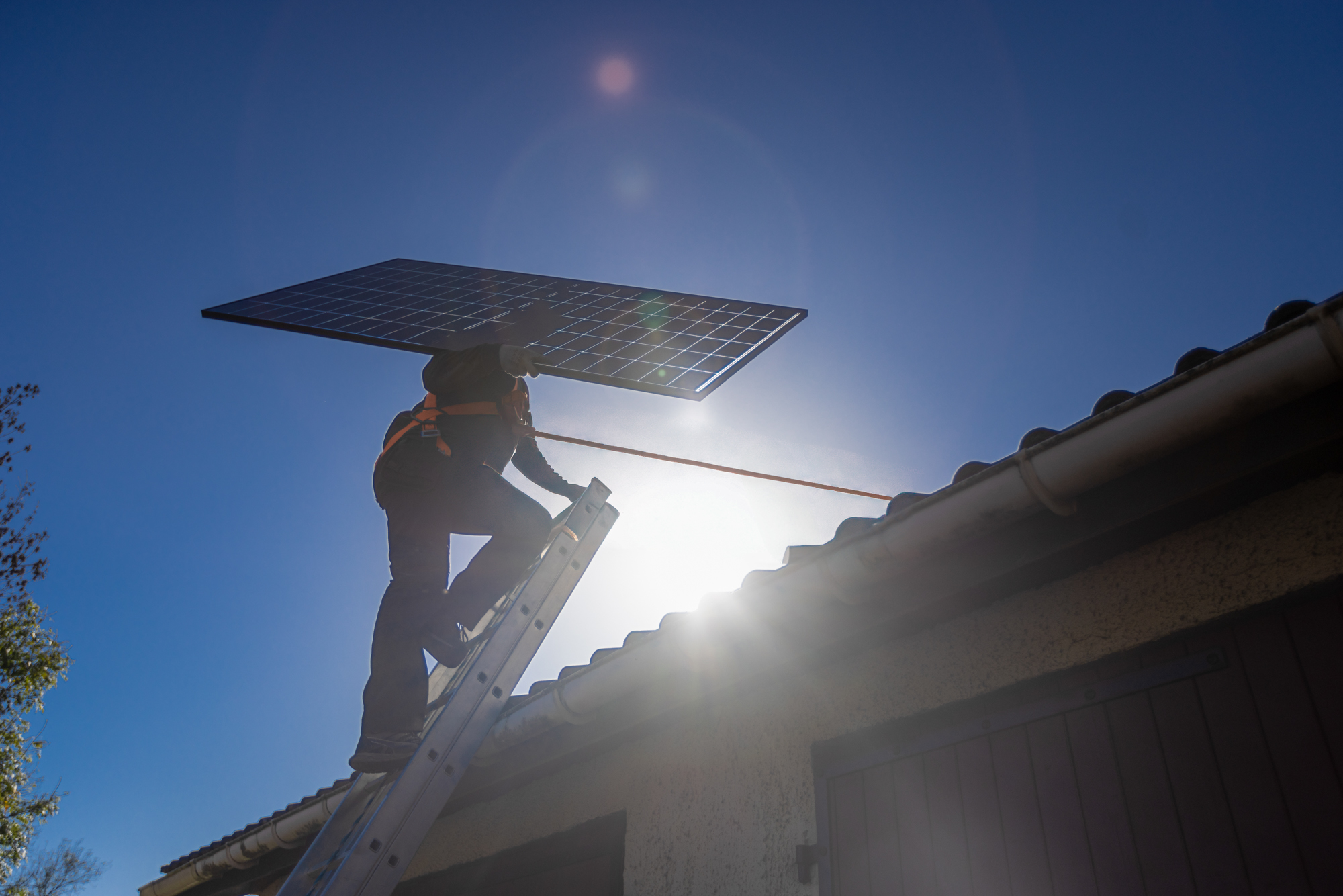 Technicien HomeServe montant sur le toit d'une maison pour y installer des panneaux solaires