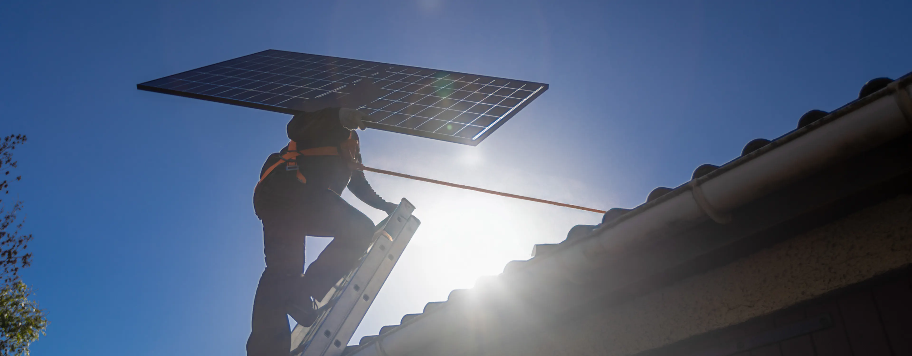 Technicien HomeServe montant sur le toit d'une maison pour y installer des panneaux solaires