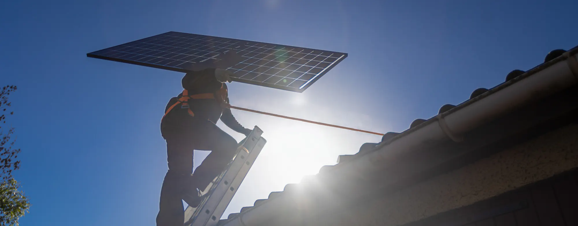 Technicien HomeServe montant sur le toit d'une maison pour y installer des panneaux solaires