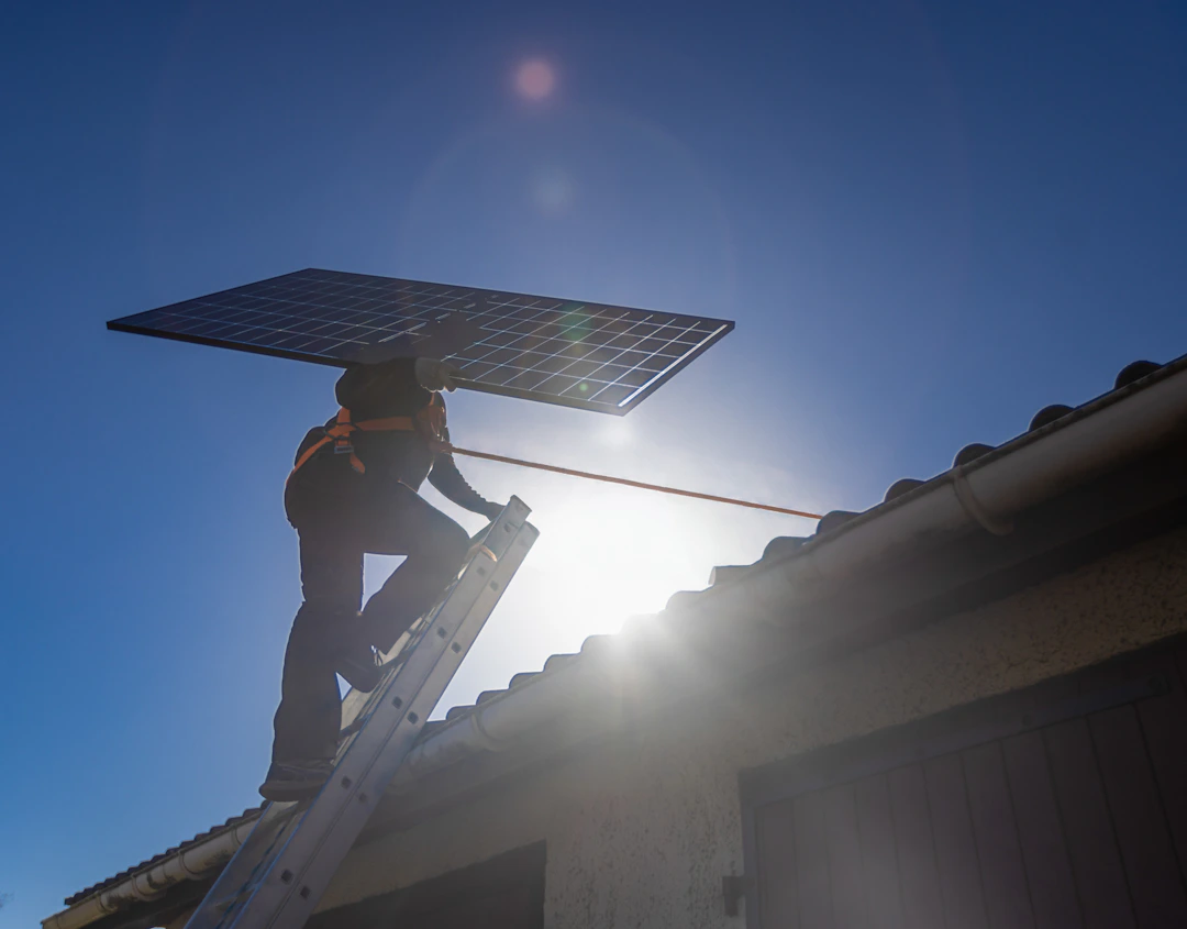 Technicien HomeServe montant sur le toit d'une maison pour y installer des panneaux solaires