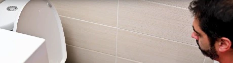 Homme avec furet électrique débouchant des toilettes dans une salle de bain
