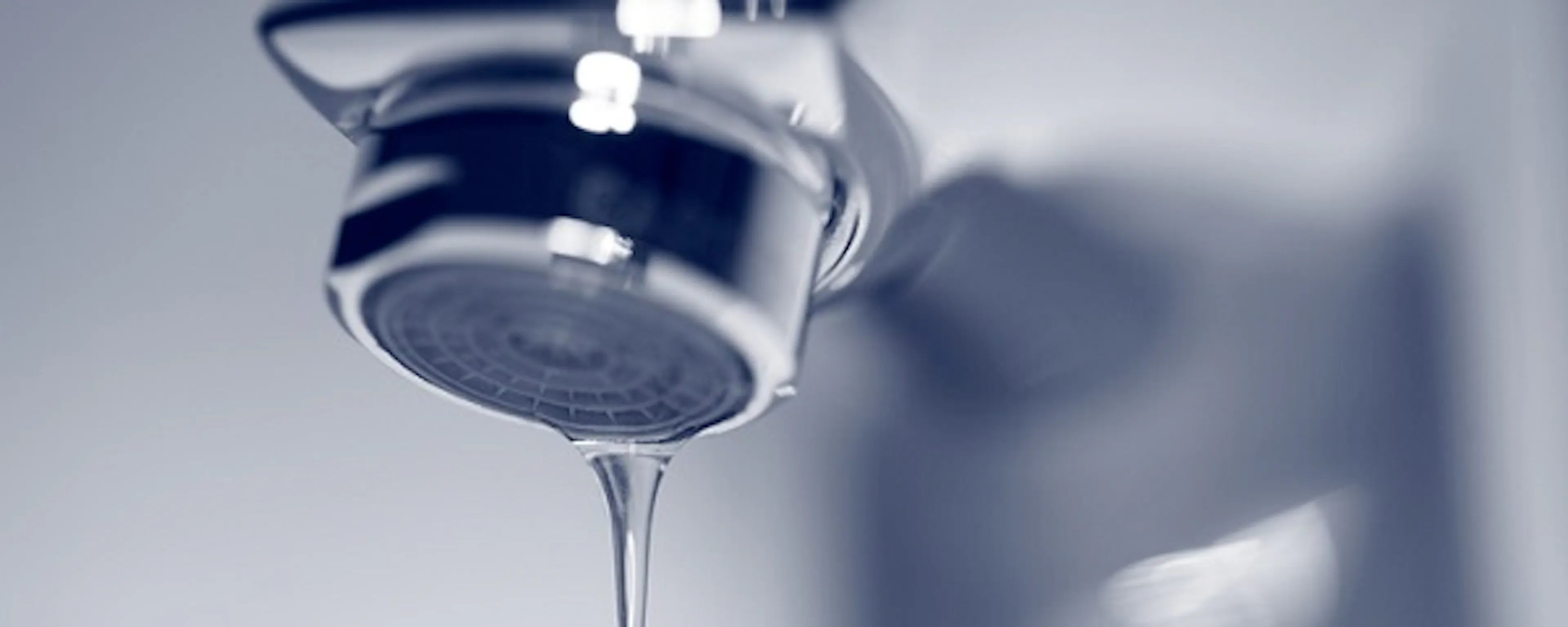 Robinet chromé avec une goutte d'eau tombant, fond bleu
