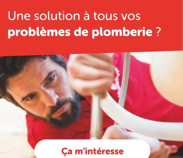 Plombier en polo rouge examinant une canalisation sous un évier