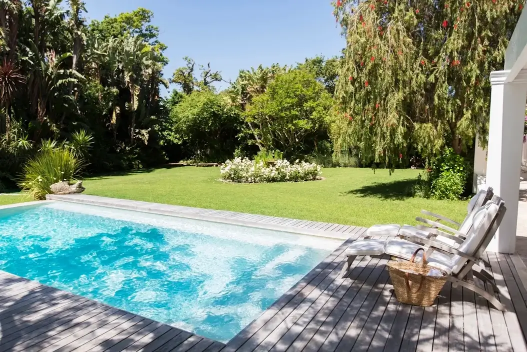 Piscine rectangulaire bleue dans un jardin verdoyant ensoleillé