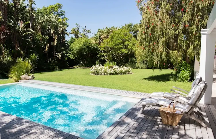 Piscine rectangulaire bleue dans un jardin verdoyant ensoleillé