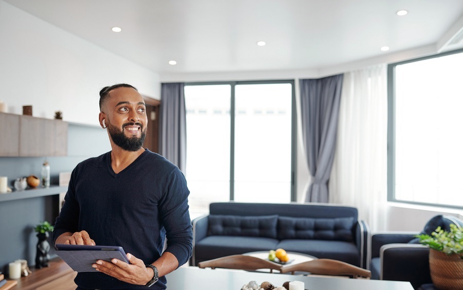 Homme souriant tenant une tablette dans un salon moderne et clair