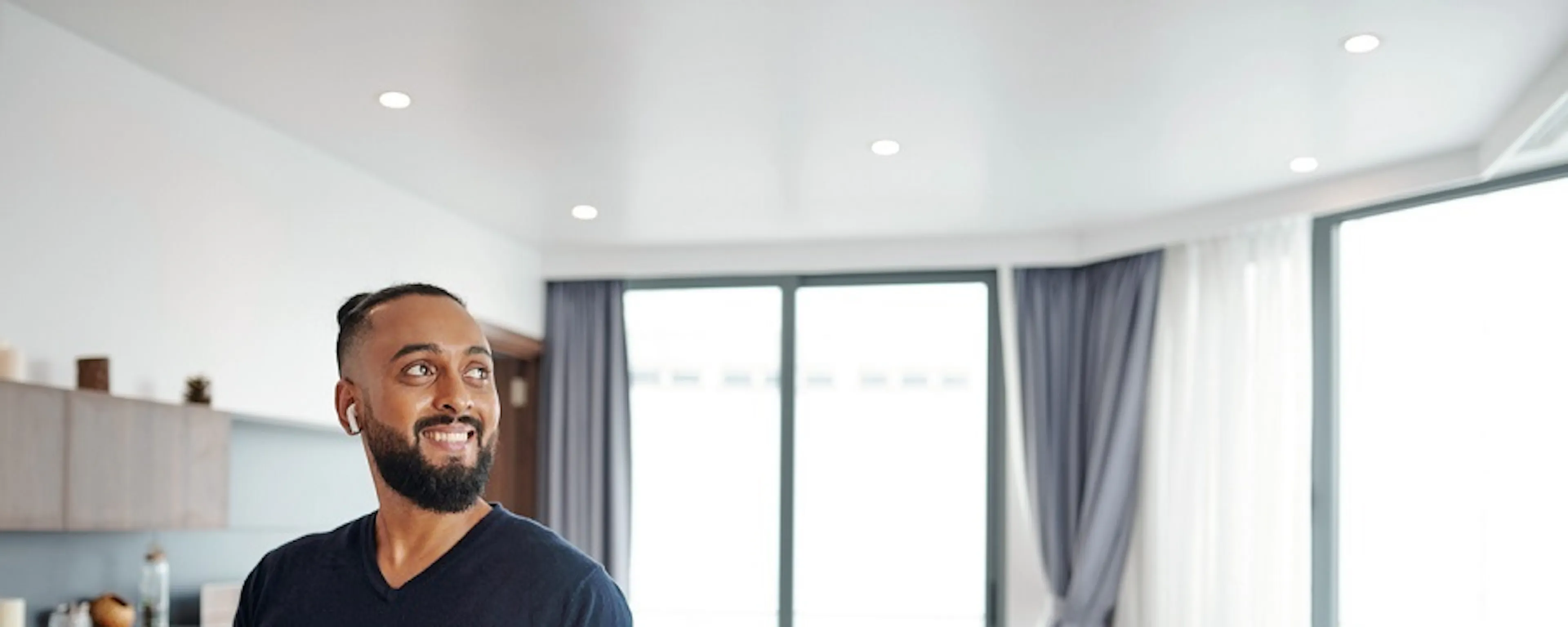 Homme souriant tenant une tablette dans un salon moderne et clair