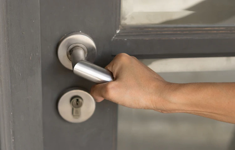 Main saisissant une poignée de porte en métal gris