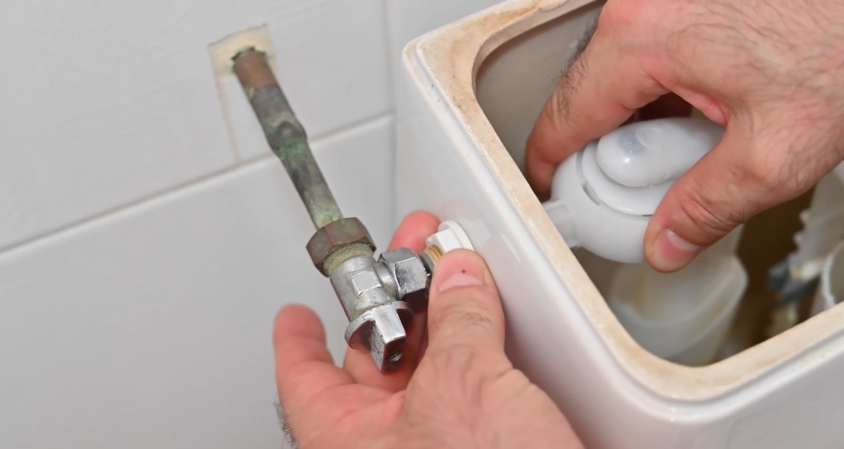 Mains remplaçant le robinet d'arrêt d'un réservoir de toilettes