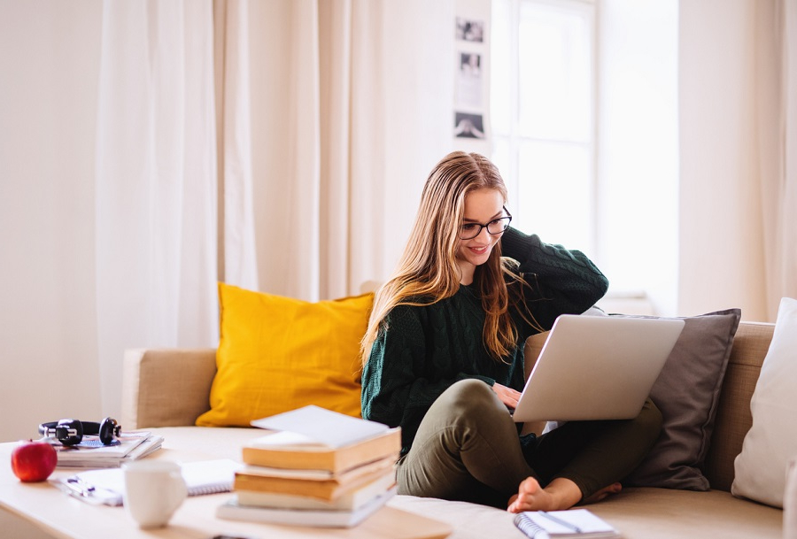 Femme assise sur un canapé travaillant sur un ordinateur portable
