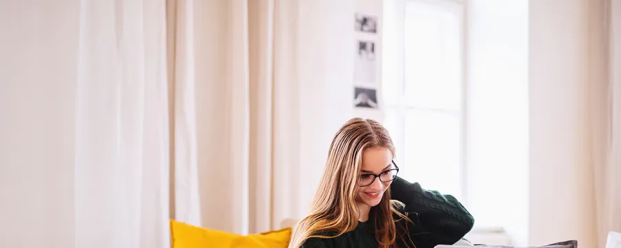 Femme assise sur un canapé travaillant sur un ordinateur portable