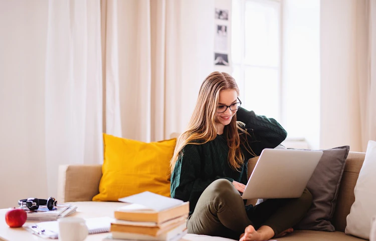 Femme assise sur un canapé travaillant sur un ordinateur portable