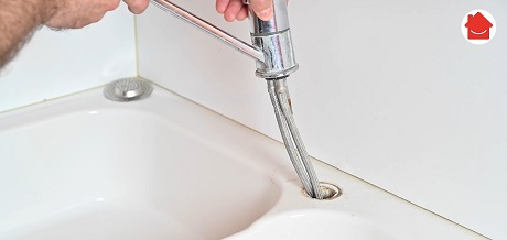 Main démontant un robinet de cuisine chromé au-dessus d'un évier