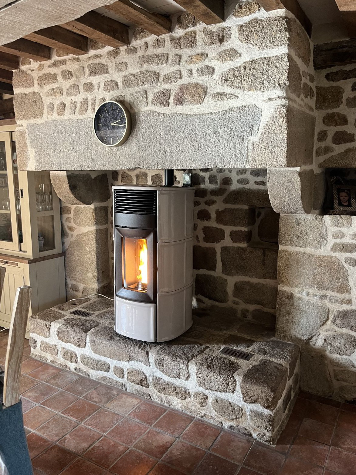 Un poêle à bois moderne installé dans une cheminée ancienne en pierre