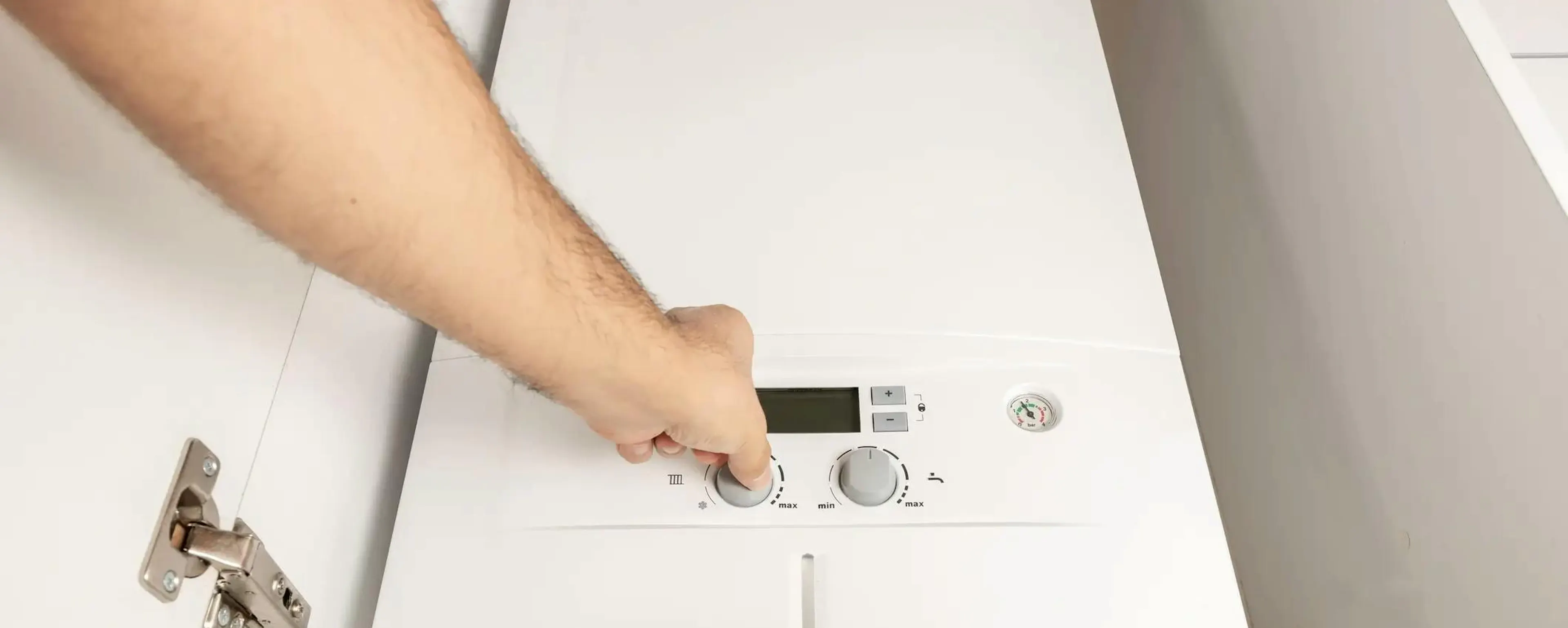 Technicien réglant une chaudière gaz murale blanche après remplacement ayant bénéficié d'aides