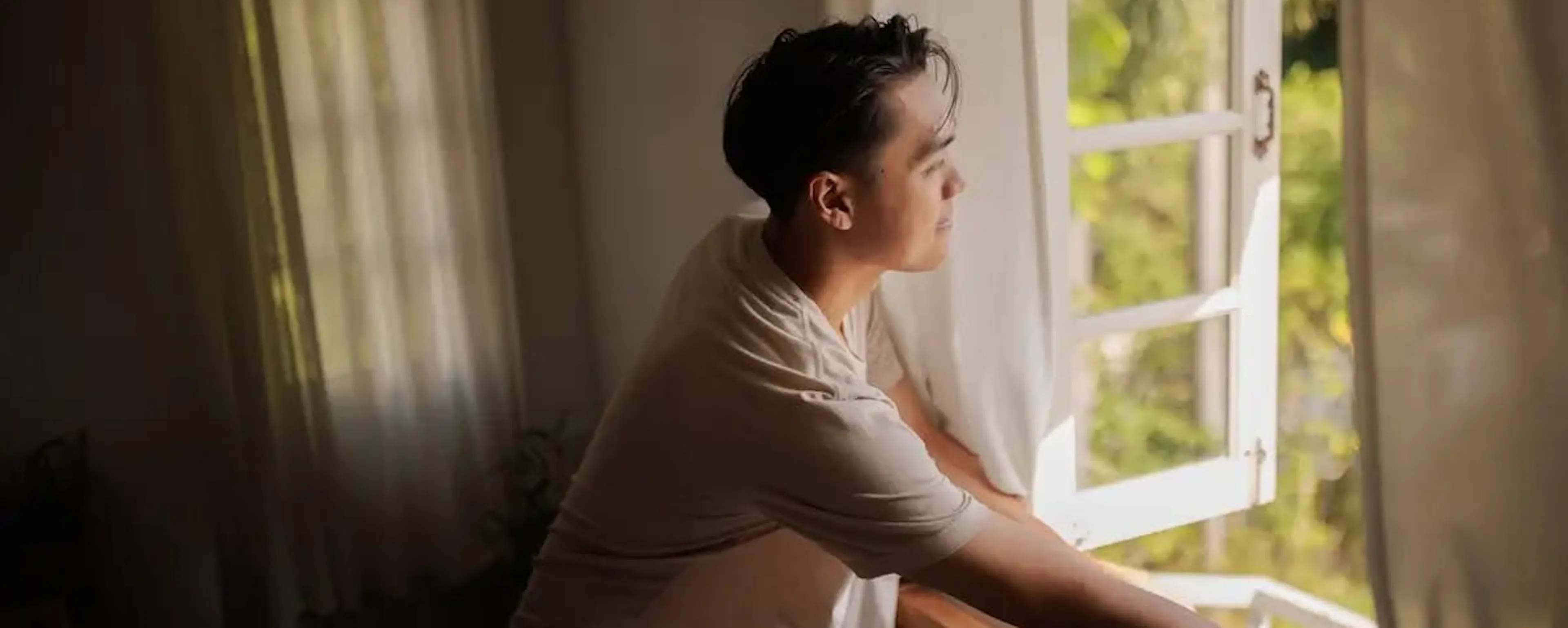 Femme regardant par une fenêtre ouverte se demandant s'il faut vraiment aérer sa maison en hiver