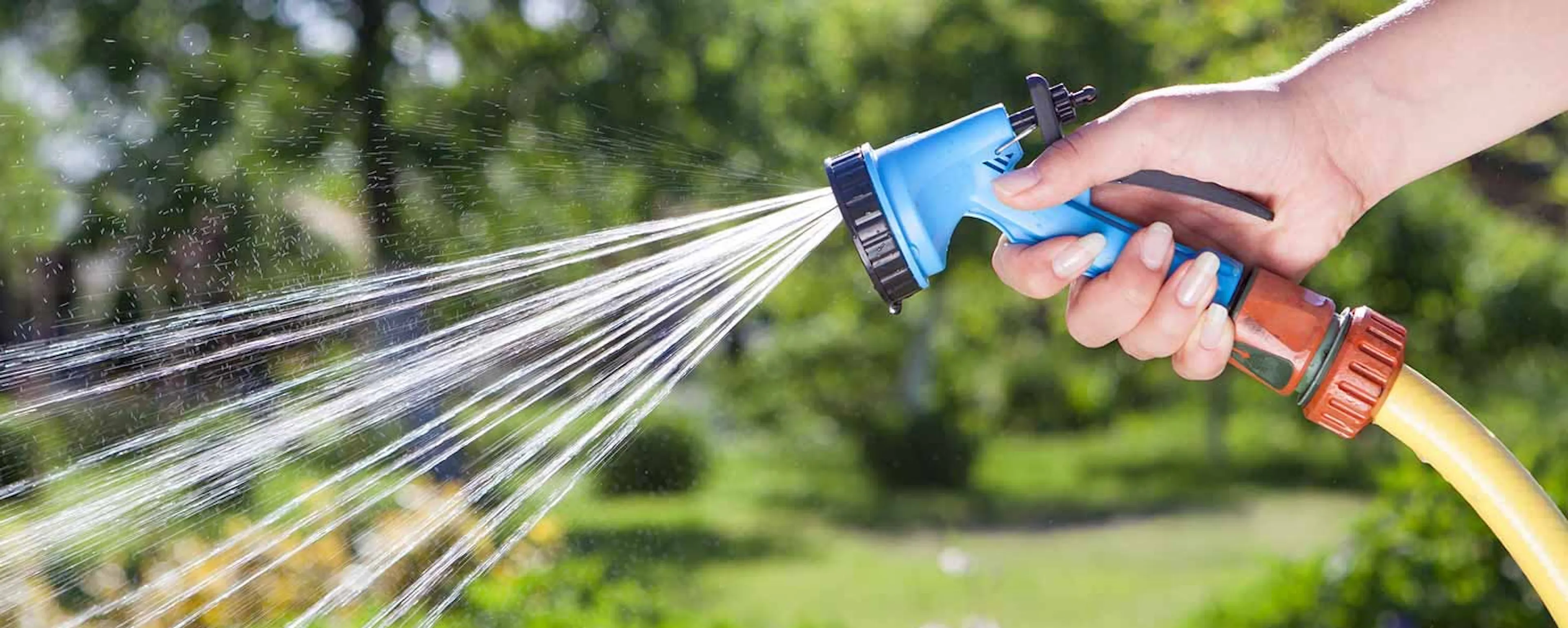 Main tenant un pistolet d'arrosage écologique pour limiter la consommation d'eau dans un jardin