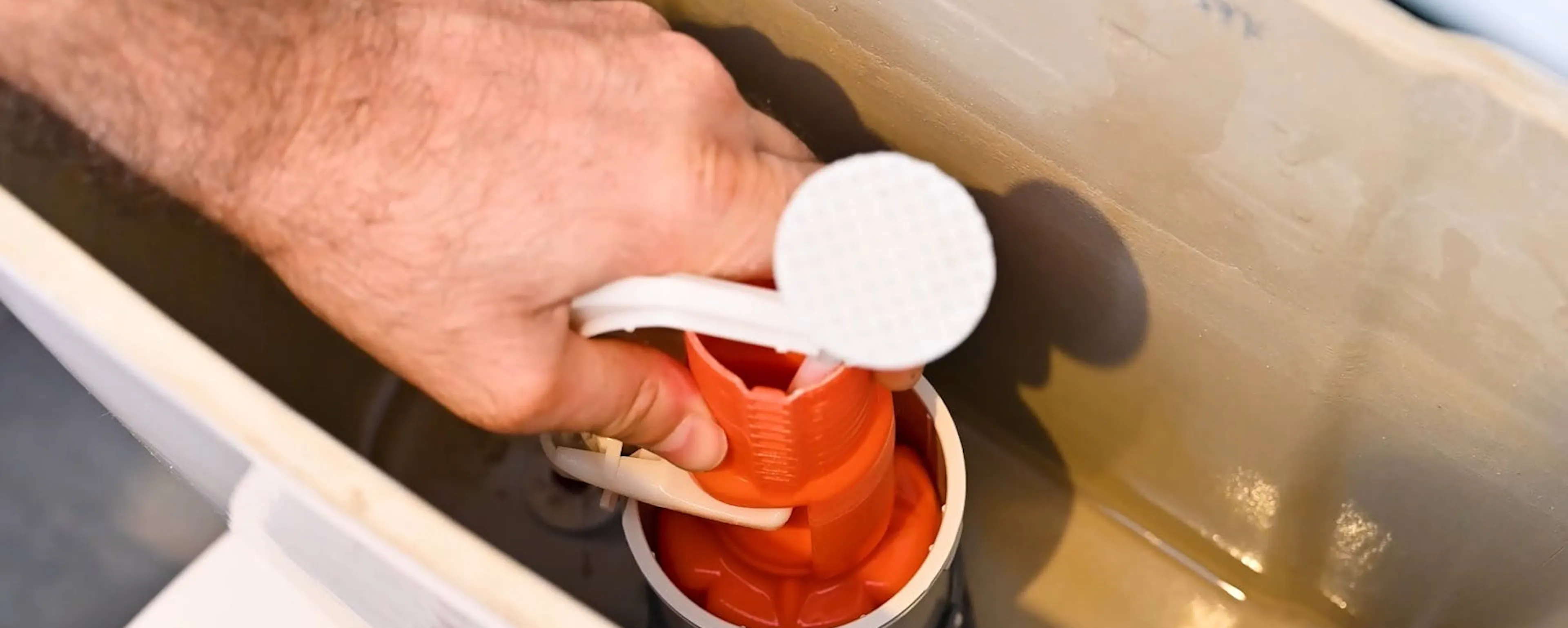 Main tenant le mécanisme intérieur d'une chasse d'eau de WC à changer