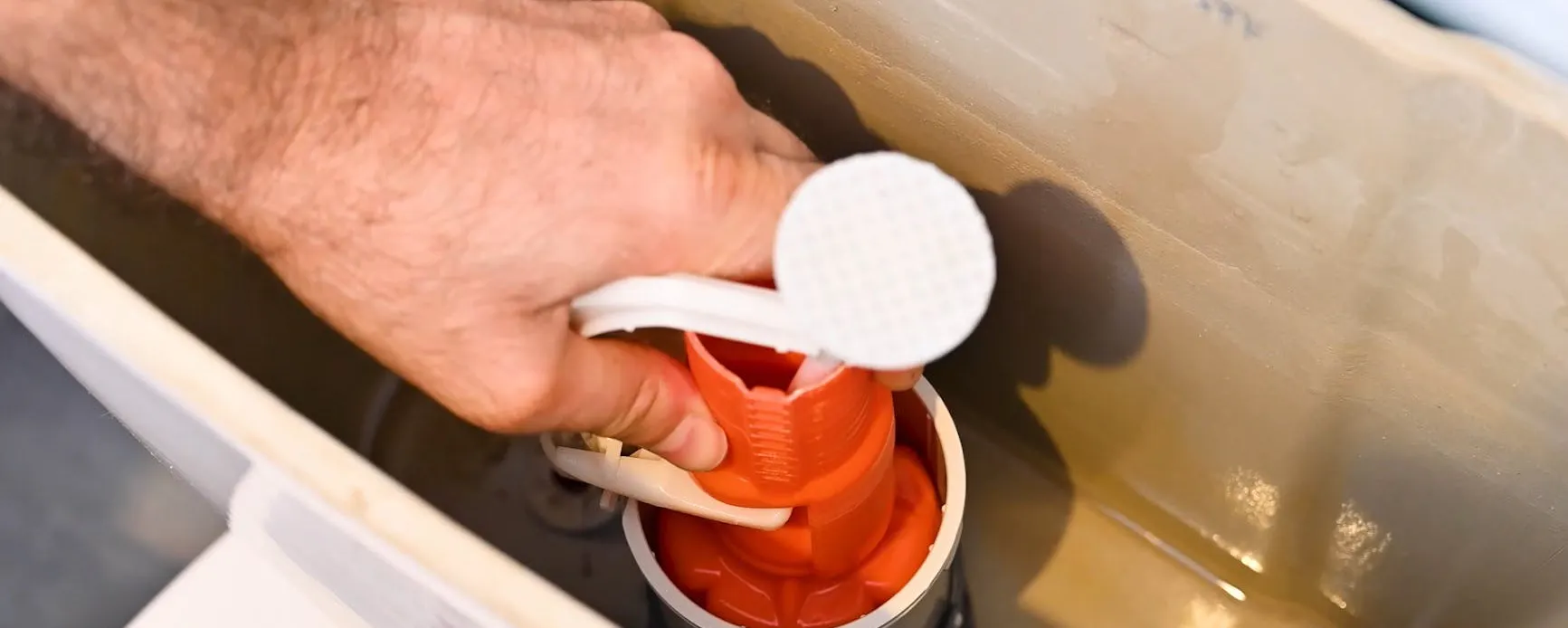 Main tenant le mécanisme intérieur d'une chasse d'eau de WC à changer