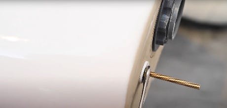 Gros plan sur une vis dorée fixée à la base d'un chauffe-eau blanc