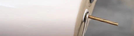 Gros plan sur une vis dorée fixée à la base d'un chauffe-eau blanc