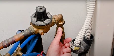 Main tenant un réducteur de pression sur un réseau de tuyaux