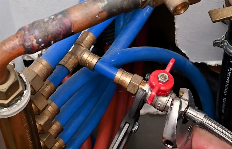 Réseau de tuyaux bleus et cuivrés avec vanne rouge en plomberie