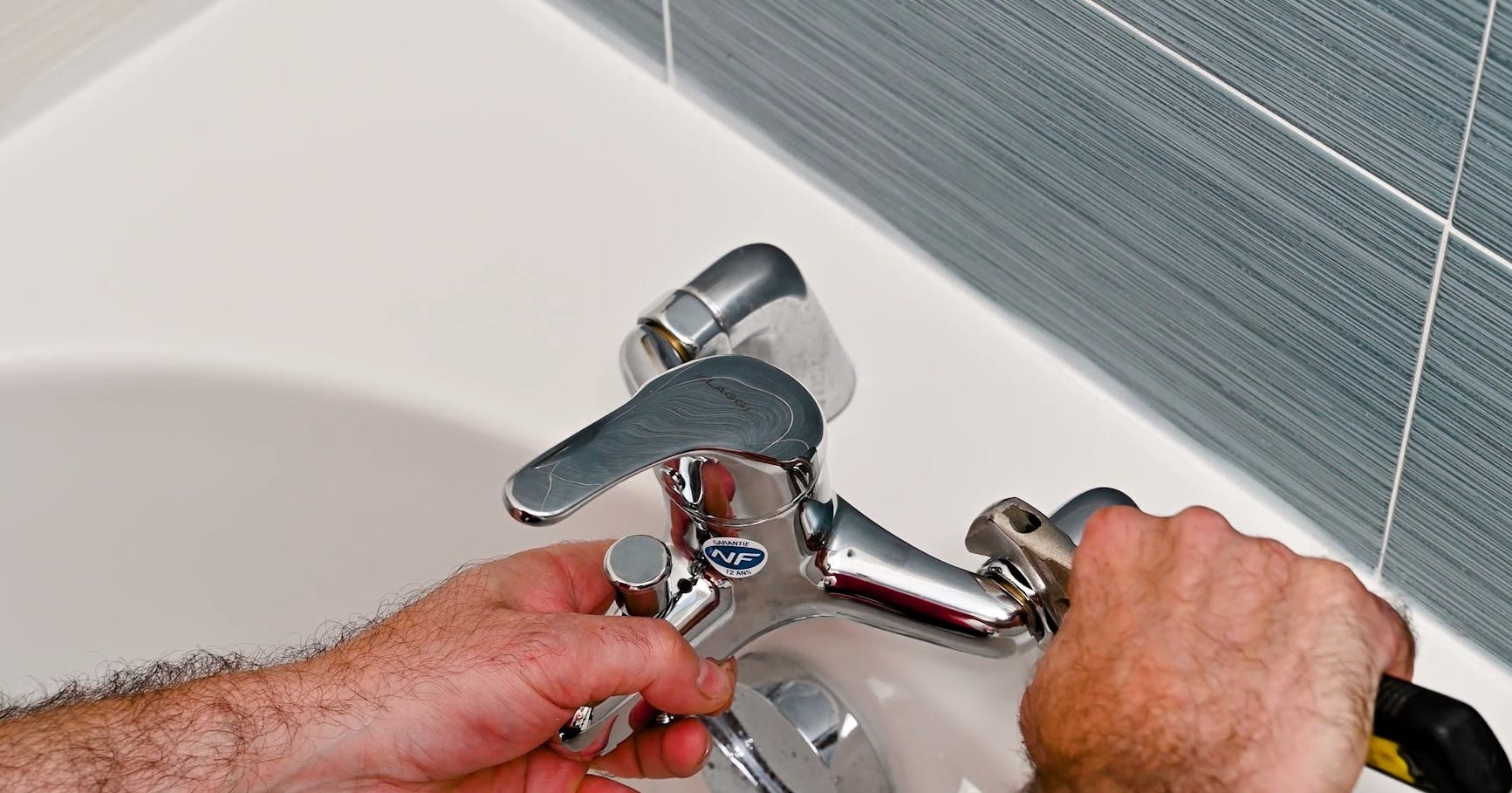 Plombier installant ou réparant un robinet mitigeur sur une baignoire