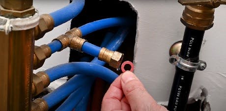 Main présentant un joint torique sur un réseau de tuyaux bleus