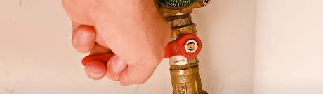 Main fermant un robinet d'arrêt en laiton sur un tuyau flexible