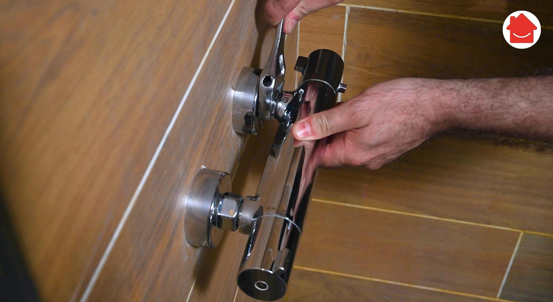 Mains ajustant une vanne thermostatique chromée sur carrelage bois
